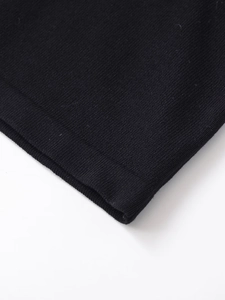 Close-up of black cotton knit fabric showing precise hem stitching and texture