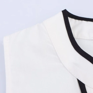 Detailopname van de witte midi-jurk met zwart contrasterende bies en fijn stiksel bij de nek