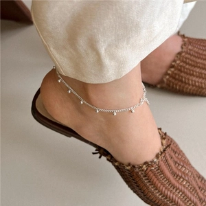 Detail shot of a minimalist 925 silver anklet with small bells on a female ankle