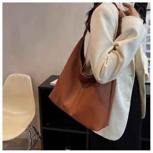 Brown leather large capacity tote bag shown on model wearing white blazer