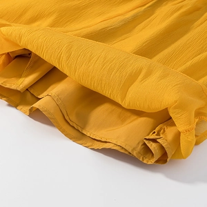 Close-up of ginger yellow top with ruffled hem and pleated texture detail