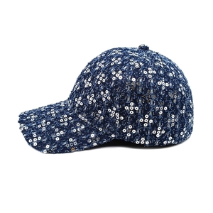 Detail of tweed baseball cap with sequined clover patterns and textured dark blue fabric