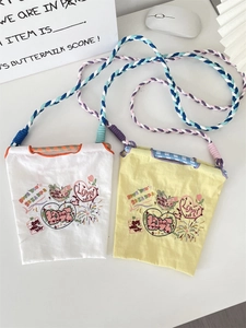 Détail de la broderie cœur sur les sacs en tissu Oxford avec bandoulières tressées colorées