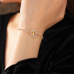 Gros plan sur le pendentif ovale Vierge Marie avec zircons sur un bracelet ajustable doré