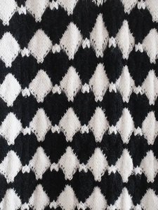 Macro view of black and white diamond pattern knit vest with soft wool texture
