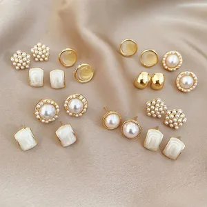 Elegant pearl and white enamel stud earring set with gold finish on silk background