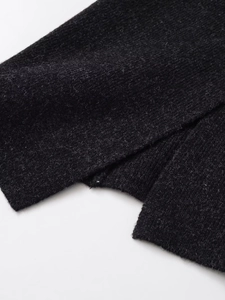 Detail of black knit midi skirt featuring high-quality wool blend texture and split hem