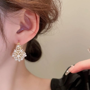 Close-up of elegant gold plated pearl drop earrings worn by a model in a side profile view