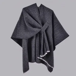 Detail of dark gray knit shawl with textured fabric and white fringe hem decoration