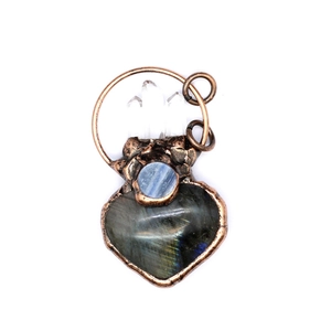 Vintage copper heart pendant with blue crystal and pink quartz on a minimalist white background