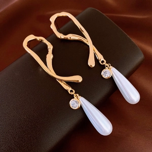 Detail of vintage French gold earrings with crystal studs and teardrop pearl drops