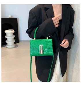 Close-up of bright green crocodile embossed leather bag with premium gold metal buckle