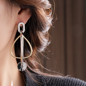 Gros plan de boucles d'oreilles pendantes géométriques bicolores portées par un mannequin