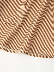 Detail shot of brown and white vertical stripes on the woven shirt dress fabric