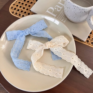 Close-up of light blue and cream lace bow hair clips with floral embroidery on ceramic