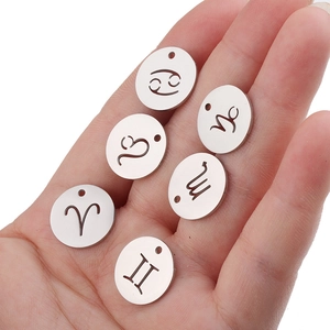 Close-up of 15mm mirror polished stainless steel zodiac charms held in a hand