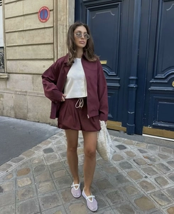 Detail of burgundy vintage jacket and matching drawstring shorts with white handbag