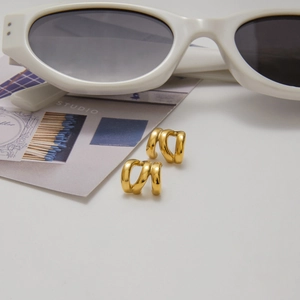 Macro view of triple-layered gold stainless steel hoop earrings on a minimalist white backdrop