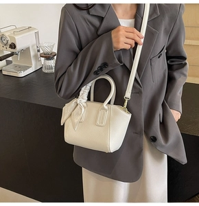 Detail of white litchi pattern bucket bag with silk scarf on handle and metal hardware