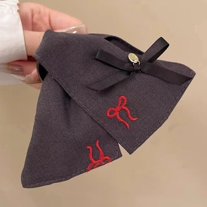 Detail of vintage black fabric bow hair clip with red embroidery and gold metal accent