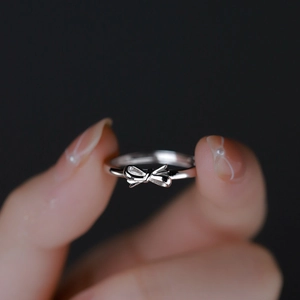Macro primo piano di un delicato anello a fiocco in argento sterling S925 sul dito
