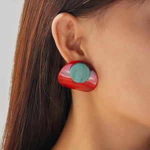Close-up of red and green acrylic drop earring worn by a model with a glossy resin finish