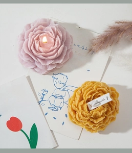 Macro di una candela profumata a forma di peonia con petali in cera in una ciotola di vetro