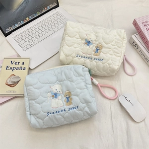 Close-up of heart-quilted cosmetic bags with lamb and puppy embroidery in soft fabric