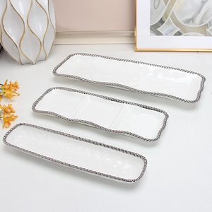 Three-piece set of white ceramic rectangular trays with silver beaded rim in home setting