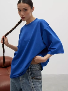 Dettaglio di una t-shirt in cotone blu Klein oversize abbinata a jeans lavati chiari