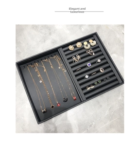 Macro view of black jewelry display tray with assorted rose gold necklaces and rings