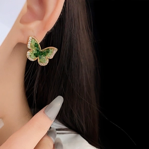 Macro view of green zircon butterfly stud earring with gold-plated sterling silver pin