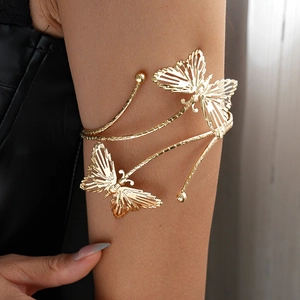 Détail d'un brassard papillon doré ajouré avec un design en spirale sur le haut du bras