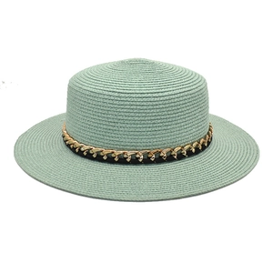Détail du chapeau de paille vert menthe avec chaîne dorée élégante sur le dessus plat