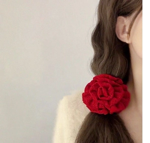 Close-up of a large red fabric rose scrunchie worn on a model's ponytail