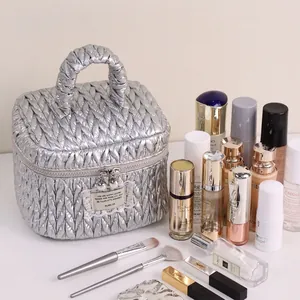 Silver quilted cosmetic bag with top handle and wave patterns on an organized vanity table