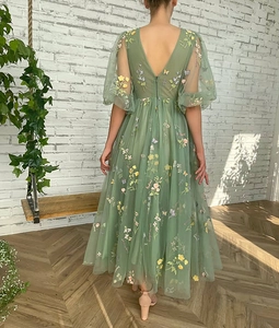 Detail of light green tulle maxi dress with colorful floral embroidery and puff sleeves