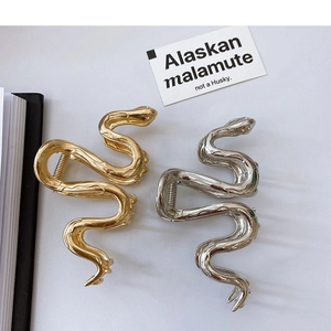 Macro detail of snake-shaped metal hair claws in gold and silver finishes