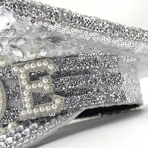 Detail of sequins and faux pearls on a captain hat with a large pearl letter E