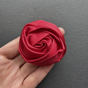 Detailed view of handmade red satin rose brooch showing silk texture and layered petals