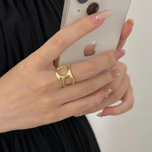 Detailed view of irregular geometric hollow ring in polished gold on a model's hand