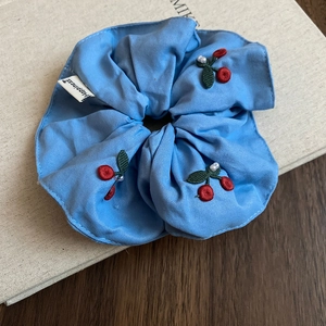 Detail of light blue knit scrunchie with cherry embroidery and small white pearls