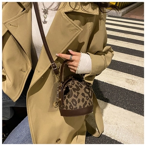 Street style shot of a leopard print bucket bag with leather trim and shoulder strap
