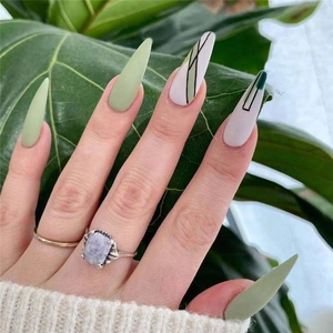 Detail of long pointed press-on nails featuring green and geometric line art designs