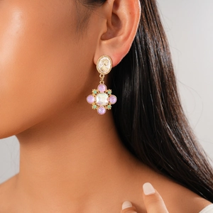 Detailed view of vintage cameo earrings with purple gemstone flower charms on model
