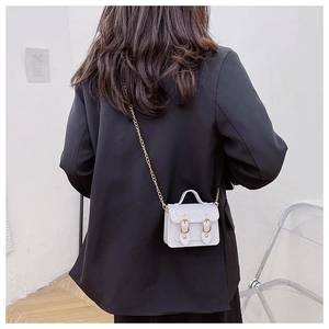 Detail view of a white PVC mini crossbody bag with a vintage flap and golden metal chain