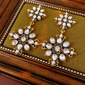 Gros plan de boucles d'oreilles fleurs dorées vintage avec cristaux et perles