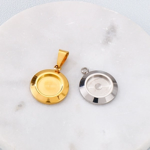 Polished gold and silver stainless steel bezel pendants on white marble background