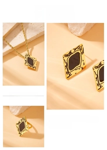 Detail of gold-plated geometric jewelry set with black rhombus inlays on stone surface