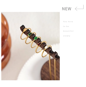Detail view of five gold titanium steel rings with assorted colorful gemstones on a stand